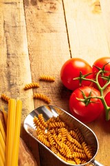 a sprig of tomatoes, Italian spaggeti and pasta. on a wooden background. culinary background. diet. tasty and healthy food, restaurant menu, homemade menu.