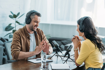 displeased radio host gesturing while sitting at workplace near colleague