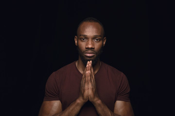Close up portrait of young man isolated on black studio background. Photoshot of real emotions of...