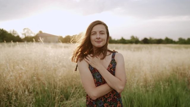 Woman looking at camera and smiling at fields with high grass. Slowmotion