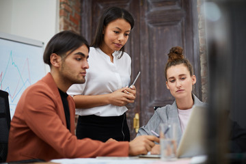 Portrait of multi-ethnic business team using laptop together while collaborating on startup project, copy space