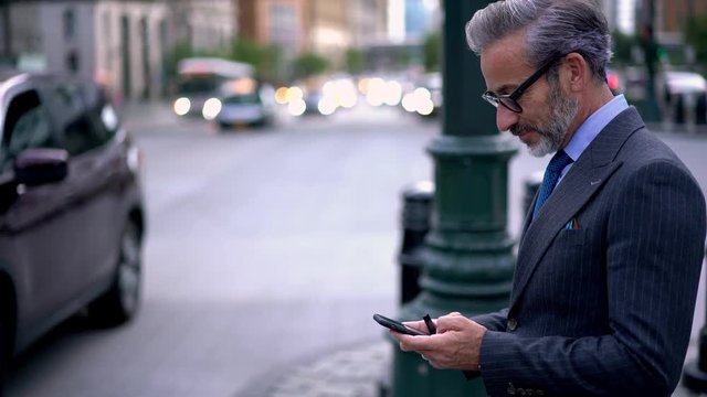 Cheerful caucasian professional expert enjoying communication with friends via application on cellular gadget while browsing financial websites in internet environment, concept of successful people
