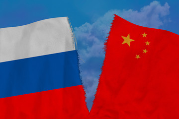 two national flags of Russia and China are torn apart by fabric, close-up, concept of diplomatic...