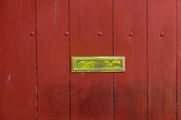 Old style brass mail slot on a wooden gate