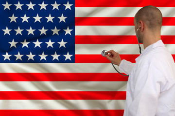 male doctor in white coat applied a medical instrument with a stethoscope to the national flag, back view, concept, copy space