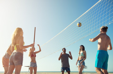 Group of friends playing at beach volley at the beach