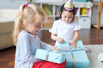 Cute blonde little girl unpacking her birthday gift