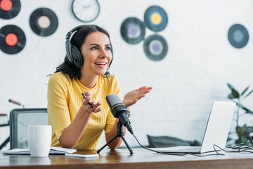 smiling radio host gesturing while recording podcast in broadcasting studio