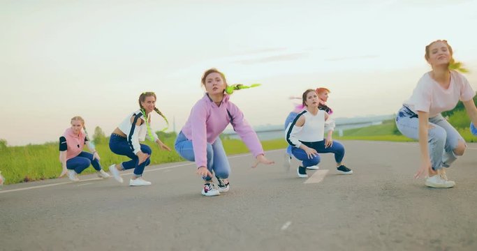 Group of young women dancing synchronously on the road. Synchronized body movements in the lower parterre.