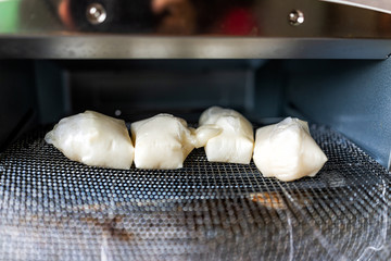 Mochi puffed up rice cake squares after being baked in toaster oven in traditional Japanese way on rack