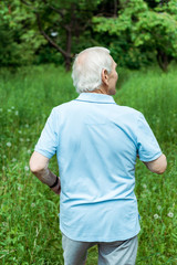 retired man with grey hair standing in green park