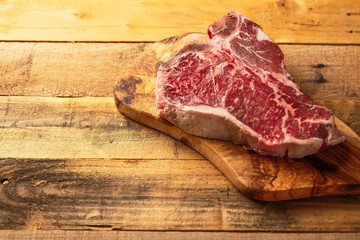 Fresh raw piece of marbled beef steak on a cutting board, on a wooden background. Restaurant menu, home menu. Delicious food, gastronomy, culinary background.