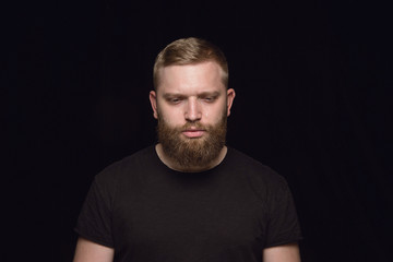 Obraz premium Bliska portret młodego człowieka na białym tle na tle czarnego studia. Sfotografowanie prawdziwych emocji modela. Płacz, smutek, ponury i beznadziejny. Wyraz twarzy, koncepcja ludzkich emocji.