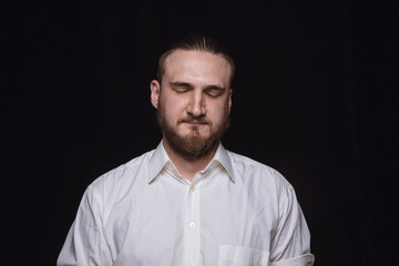 Obraz premium Close up portrait of young man isolated on black studio background. Photoshot of real emotions of male model. Crying with closed eyes, sad and hopeless. Facial expression, human emotions concept.
