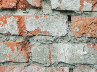 Background old masonry of red brick. Plaster, concrete, cement. Cracks, peeling, voids. Close-up.