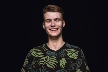 Close up portrait of young man isolated on black studio background. Photoshot of real emotions of male model. Crying throught laughting and smiling. Facial expression, human emotions concept.