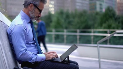  50 years old entrepreneur formally dressed communicating via mobile app while working with report via online platform in browser, man having international smartphone conversation on urban setting