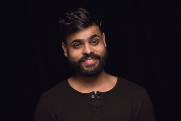Obraz premium Close up portrait of young man isolated on black studio background. Photoshot of real emotions of male model. Crying throught laughting and smiling. Facial expression, human emotions concept.