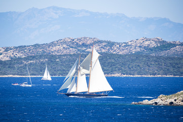 Stunning view of a beautiful sailboat sailing on the Mediterranean sea that bathes the coasts of Sardinia. Maddalena Archipelago National Park in the background, Sardinia, Italy.