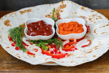 Red pepper, pomegranate seeds, parsley leaf on fried pita bread. The substrate for delicious grilled meat. Meat sauces, ketchup, Armenian Aivar. Horizontal close-up photo.