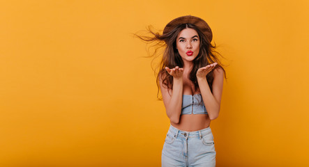 Wonderful tanned girl with red lipstick having fun on yellow background. Cheerful young female...