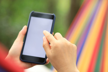Relaxing in hammock with smartphone in forest