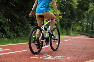 Woman riding bike on sunny park trail with no handed