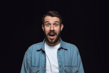Obraz premium Close up portrait of young man isolated on black studio background. Photoshot of real emotions of male model. Wondering, exciting and astonished. Facial expression, human emotions concept.