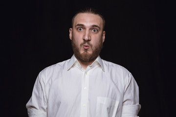 Close up portrait of young man isolated on black studio background. Photoshot of real emotions of male model. Wondering, exciting and astonished. Facial expression, human emotions concept.