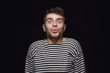 Obraz premium Close up portrait of young man isolated on black studio background. Photoshot of real emotions of male model. Wondering, exciting and astonished. Facial expression, human emotions concept.