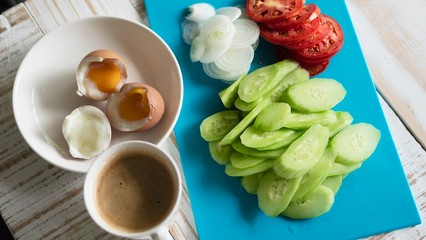 Boiled eggs with fresh cucumber salad and coffee cup breakfast set - top view breakfast food concept