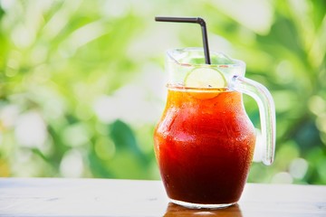 Ice tea on wooden table over green garden background - relax with beverage in nature concept