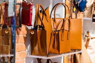 Many leather purse bags in Siena Italy with orange brown color hanging on display in shopping...