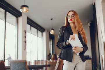 Stylish woman standing in a restaurant. Businesswoman working at the cafe. Girl use the tablet. Lady in a glasses