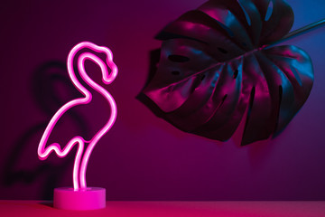 Summer pink flamingo and monstera leaf with neon pink and blue light.vacation background.