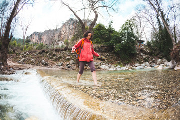 Barefoot girl crossed the mountain river.