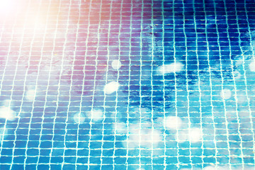 Fototapeta na wymiar Swimming pool tiling with deep blue mosaic. .Blue bottom of swimming pool refractioned by water ripple with reflection on water surface and bokeh ,used for background.