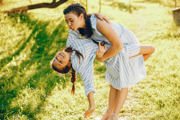 a pretty and a beautiful long-haired mom in a blue dress standing in a solar park and playing with...