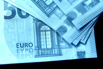 Fototapeta na wymiar Fifty euro notes on a dark background close up. Blue color toned