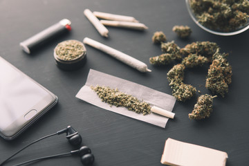 grinder in hand with fresh marijuana, close up, joint with weed, Cannabis buds on black table,
