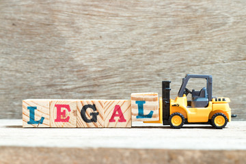 Toy forklift hold letter block l to complete word legal on wood background