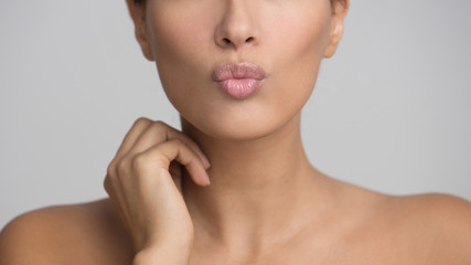 Obraz na płótnie Canvas Woman Sending Air Kiss, Pouting Lips Over Grey Background