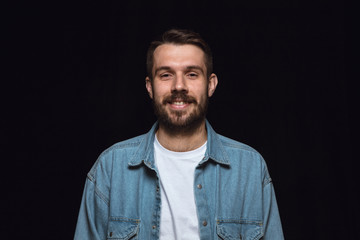 Close up portrait of young man isolated on black studio background. Photoshot of real emotions of...