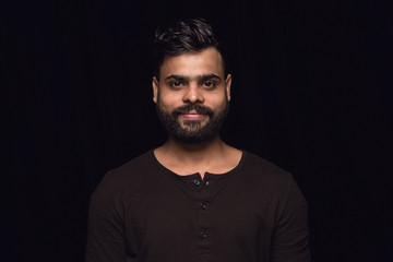 Close up portrait of young man isolated on black studio background. Photoshot of real emotions of...