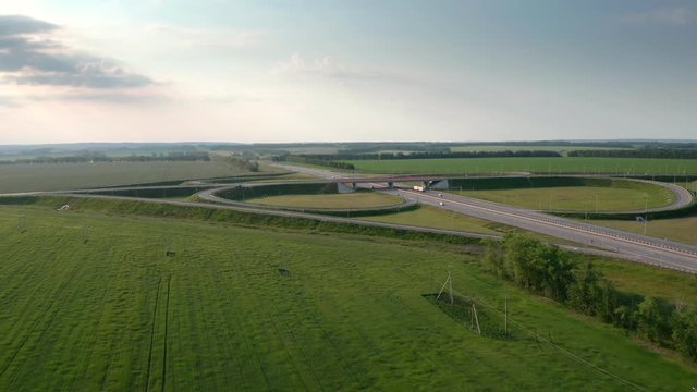 Aerial panoramic tripod shot. Around intarchange on a countryside highway.Passing heavy duty trucks.