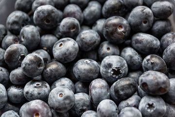 Ripe tasty blueberries and berries on a wooden table in a bowl
