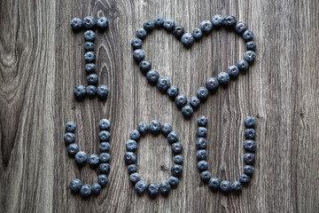 Ripe tasty blueberries and berries on a wooden table with I love you words