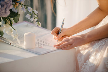 the bride in a wedding dress signs in the contract