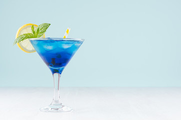 Glamour tropical fruit blue cocktail with curacao, ice cubes, lemon slice, yellow straw, mint in...