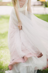 Fototapeta na wymiar The legs of the bride in a wedding dress in shoes